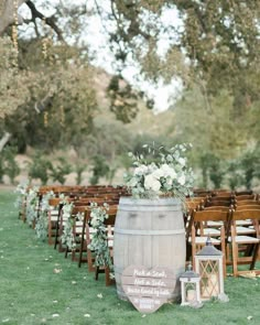 an outdoor ceremony setup with wooden barrels and white flowers