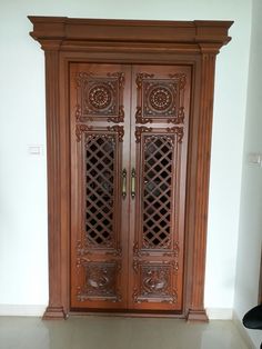 an ornate wooden door with intricate carvings on the front and side panels, in a white room