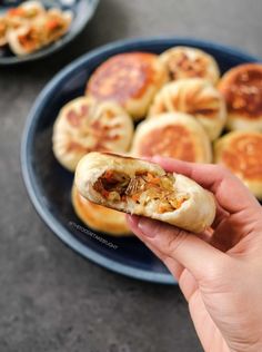 a person is holding a hot dog bun in front of some food on a plate