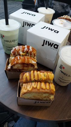 some food is sitting on a table with cups and milkshakes next to it