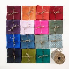 many different colored pieces of cloth tied together with twine on white background, including one roll of twine and two spools of twine