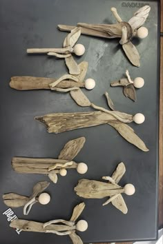 several pieces of driftwood are displayed on a black surface with white balls and wood sticks