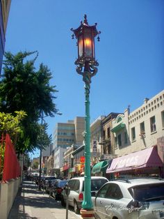 a lamp post on the side of a street with cars parked in front of it