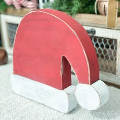 a red and white wooden object sitting on top of a rug next to a christmas tree