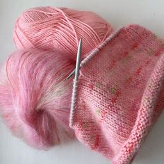 two skeins of pink yarn next to each other with a needle in the middle