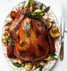 a roasted turkey on a platter with stuffing and garnished with fresh herbs