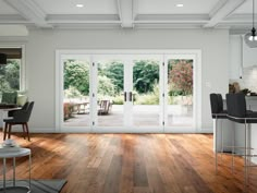 an open living room and dining area with french doors leading to the patio, wood flooring and white walls