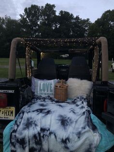 a bed in the back of a pick up truck with lights and blankets on it