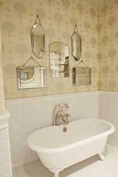 a white bath tub sitting under three mirrors