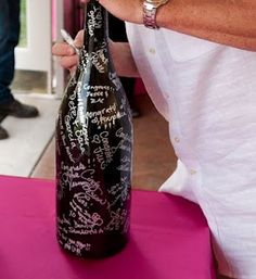 a man is holding a wine bottle with writing on it