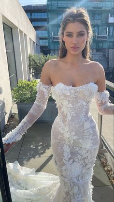 a woman in a white wedding dress standing on a balcony with her arms out to the side