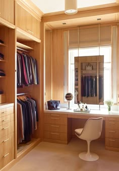 a dressing room with wooden cabinets and clothes hanging on the walls, along with a white chair