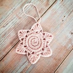 a crocheted ornament hanging from a string on a wooden floor with wood planks