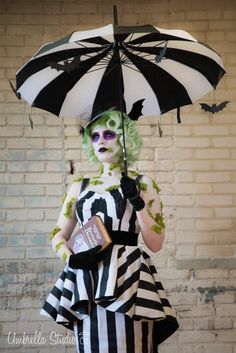 a woman dressed in black and white holding an umbrella