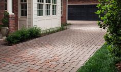 a red fire hydrant sitting on the side of a brick road next to a house