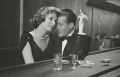 an old black and white photo of a man and woman sitting at a bar together