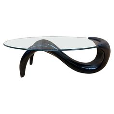 a glass and metal coffee table with curved legs