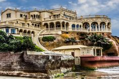 a large building on top of a hill next to the ocean with stairs leading up to it