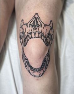 a tattoo on the leg of a person with an open mouth and teeth in black ink