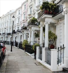 a row of white houses with balconies and plants on the balconies