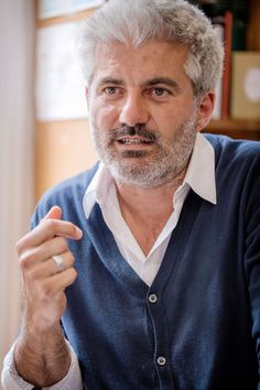 a man with grey hair and beard wearing a blue sweater