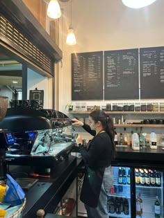 a woman standing in front of a counter filled with drinks and coffee machines at a cafe