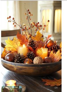 a wooden bowl filled with candles and autumn leaves