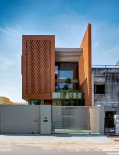 an orange brick building is next to a white fence