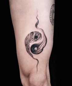 a woman's leg with a tattoo on it that has a yin symbol in the middle