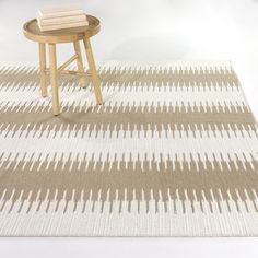 a table with a stool on top of it in front of a white and brown rug