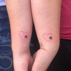 two people with tattoos on their arms holding each other's hands and one has an arrow in the shape of a heart