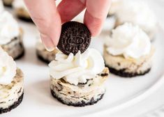 an oreo cookie being dipped into some cookies on top of white frosted cupcakes