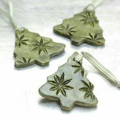 three ceramic christmas ornaments are shown on a white tablecloth, one is green and the other is silver