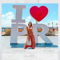 a woman standing in front of the i love paris sign with her cell phone to her ear