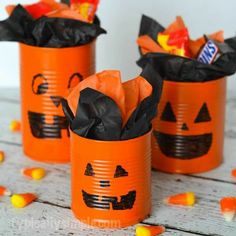 three orange tin canisters decorated with candy corn and jack - o'- lantern faces