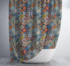 a colorful shower curtain hanging on the side of a bathtub in front of a white wall