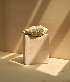 a small white bag with a rock in it sitting on a table next to a wall