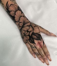 a woman's hand with black and white flowers tattooed on the left side of her arm