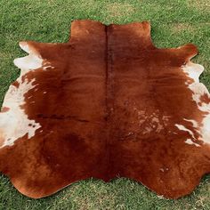 a brown and white cowhide rug on grass