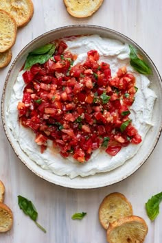 a bowl filled with whipped cream and garnished with fresh basil on top, surrounded by slices of bread