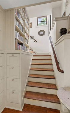 there is a staircase with bookshelves and drawers on the wall next to it