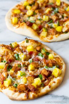 two small pizzas sitting on top of a white marble counter next to each other