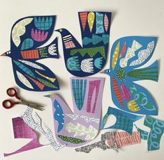 cut out paper birds sitting on top of each other next to scissors and tape measure