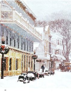 a snowy street scene with cars parked on the side and people walking down the sidewalk