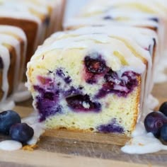 blueberry muffins with icing and fresh berries on a wooden cutting board