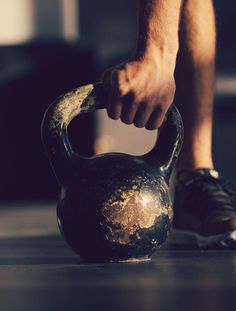 a man is holding an old kettle on the floor with one hand and another leg