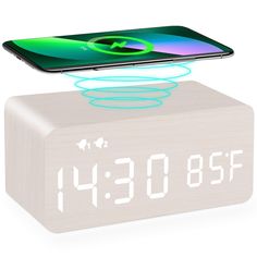 an alarm clock is shown with the phone on it's back and in front of it