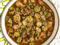 a white bowl filled with meat and vegetable stew on top of a green table cloth