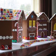 gingerbread houses are lined up on a table with candy canes and candies