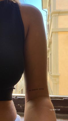 a woman with a small tattoo on her left arm and right arm behind her back